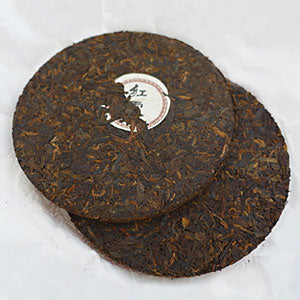 Two round, dark brown tea cakes on a white background