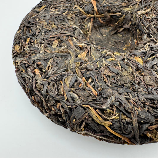 Close-up of a compressed tea cake with dried tea leaves on a white background