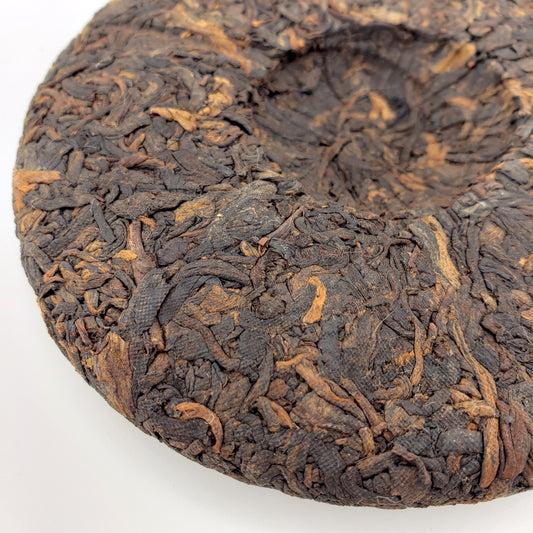 Close-up of a compressed tea cake with intricate texture on a white background