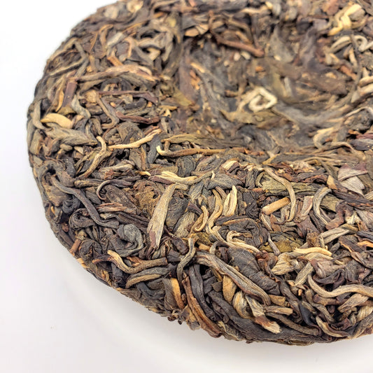 Close-up of a round cake of compressed tea leaves on a white background