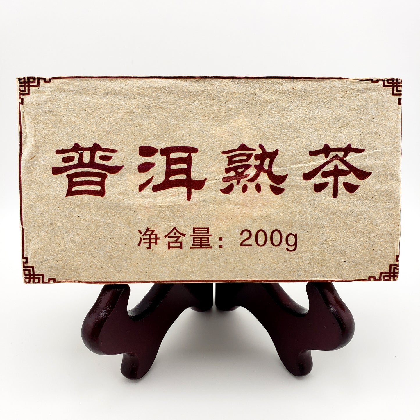 Tea brick with white and red packaging. Text reads "200 g" and Chinese text states "Pu-erh ripe tea"