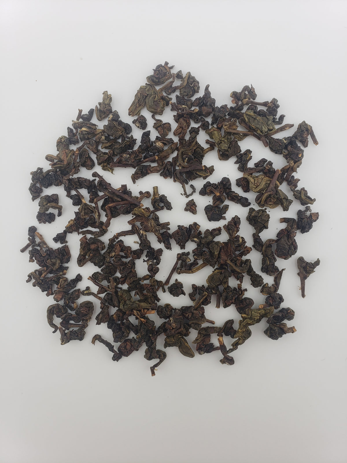 A pile of dark, tightly rolled loose-leaf tea on a plain white background.