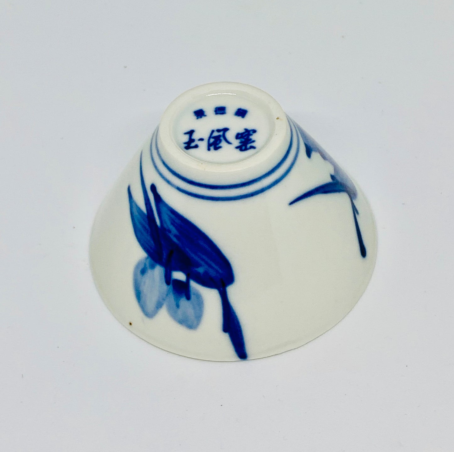 Small ceramic cup with blue floral design on a white background