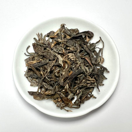 Dry tea leaves on a white plate with a white background