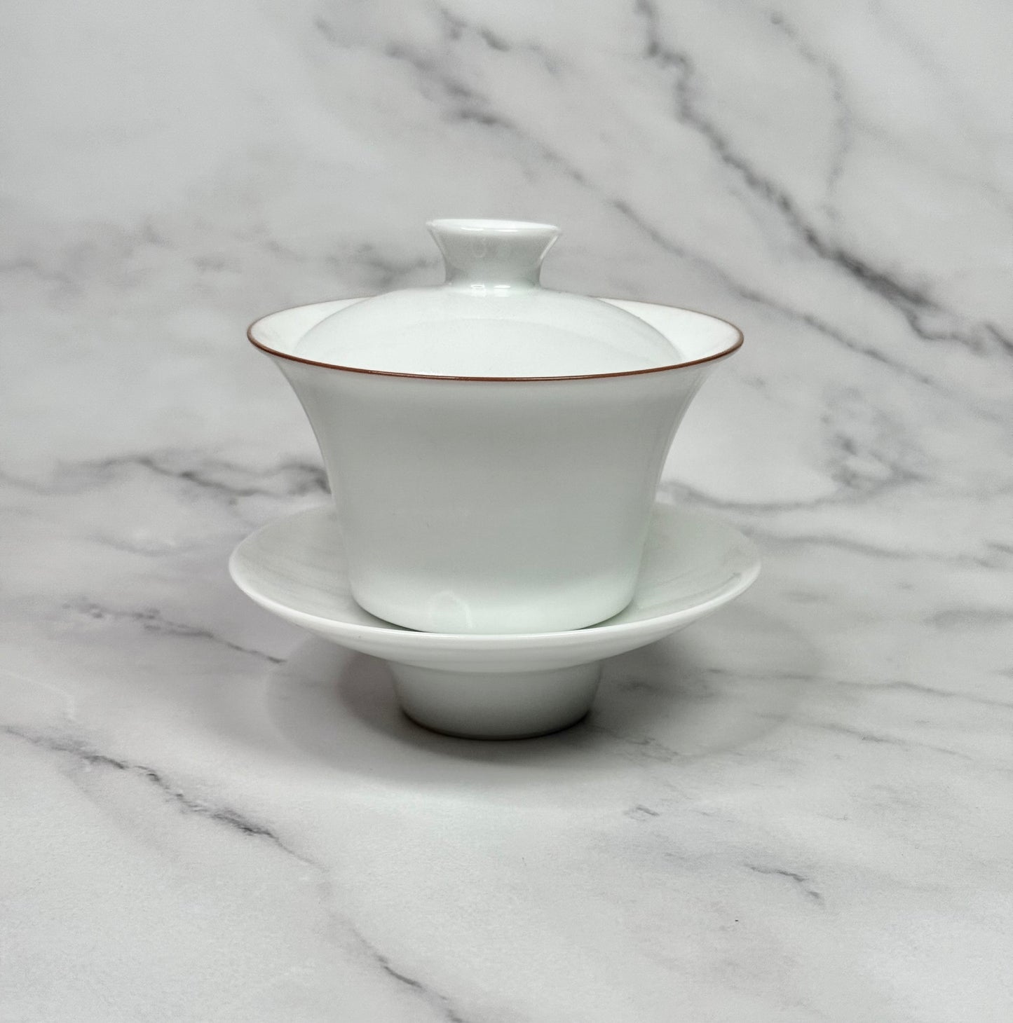 White ceramic teapot with lid on a marble surface