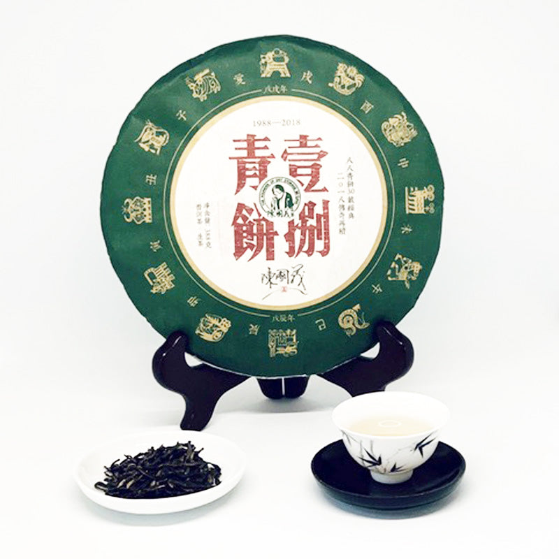 Tea cake with green packaging, tea leaves, and a teacup on a white background