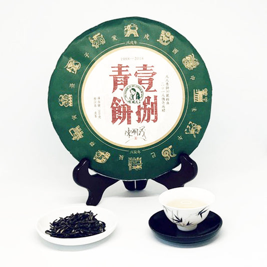Tea cake with green packaging, tea leaves, and a teacup on a white background