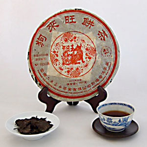 Traditional Chinese tea cake with a teacup and tea leaves on a white background