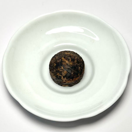 Compressed pu-erh tea on a white plate with a white background