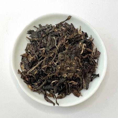Dry tea leaves on a white plate with a white background