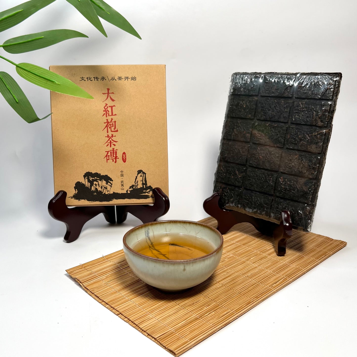 Tea bricks on a stand with a bowl of tea and a box on a white background