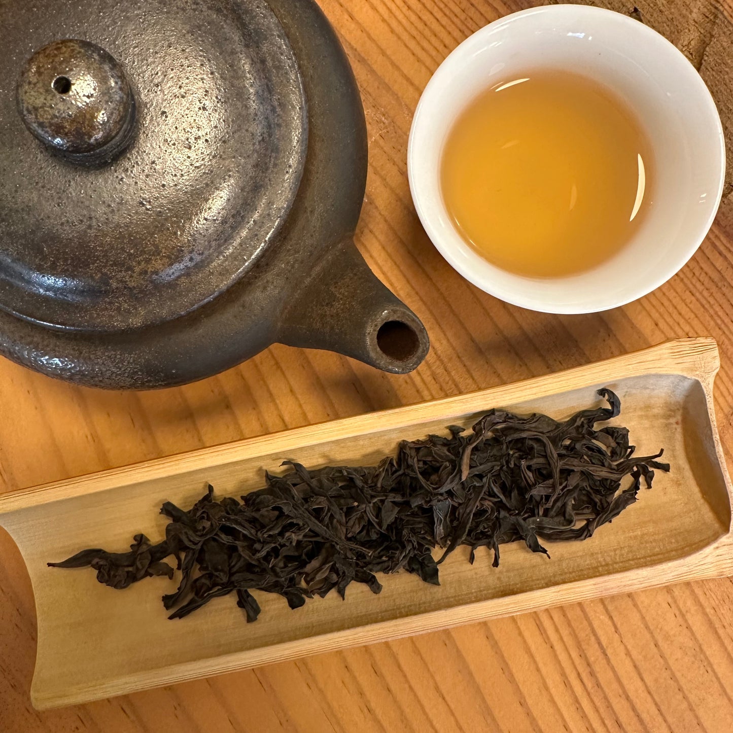 Tea set with teapot, cup of tea, and tea leaves on a wooden surface