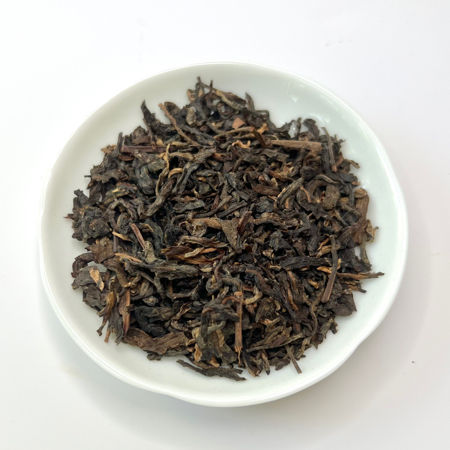 Dry tea leaves on a white plate with a white background
