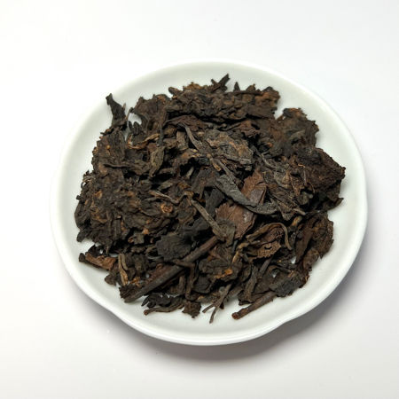 Dry tea leaves on a white plate with a white background