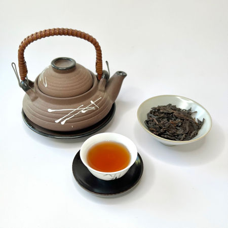 Tea set with a teapot, cup, and bowl of tea leaves on a white background