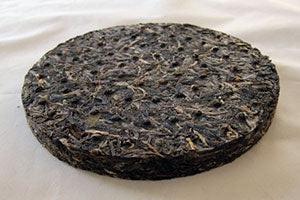 Round black tea cake on a white background