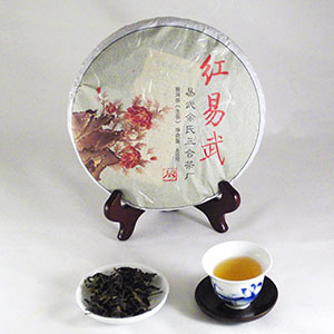 Tea cake on a stand with a cup of tea and a bowl of loose tea leaves on a white background