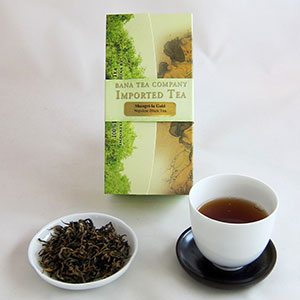 Tea packaging, a cup of tea, and a bowl of loose tea leaves on a white surface.