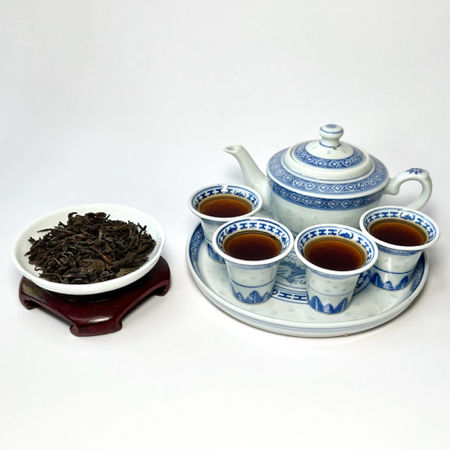 Tea set with teapot, cups, and a bowl of tea leaves on a white background