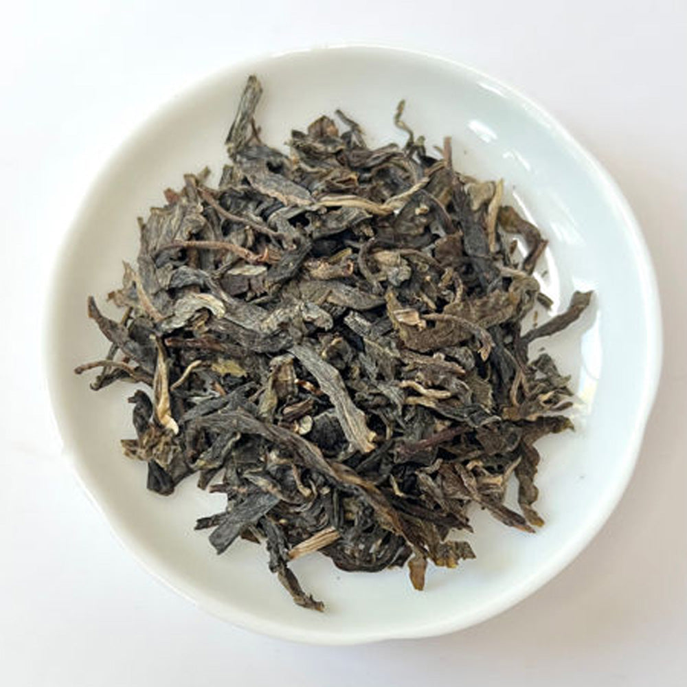 Dry tea leaves on a white plate with a plain background