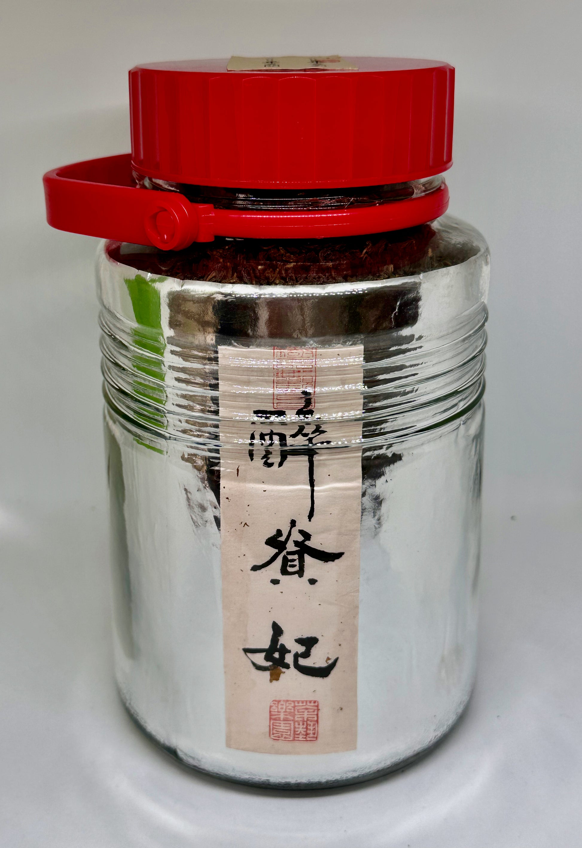 Silver jar with red lid on a white background