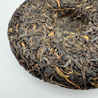 Close-up of a compressed tea cake with dried tea leaves on a white background