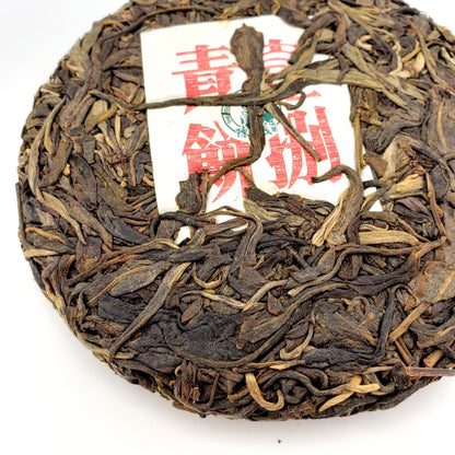 Round cake of compressed tea leaves with a red and white label on a white background