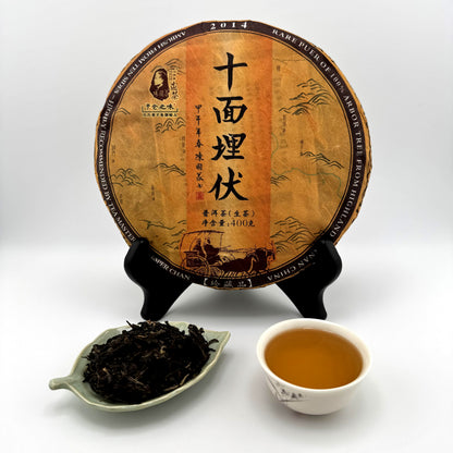 Tea cake with Chinese text, a bowl of tea, and a dish of tea leaves on a white background
