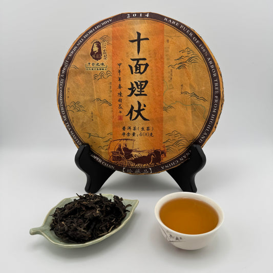 Tea cake with Chinese text, a bowl of tea, and a dish of tea leaves on a white background