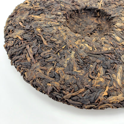 Close-up of a large Pu-erh tea cake on a white background