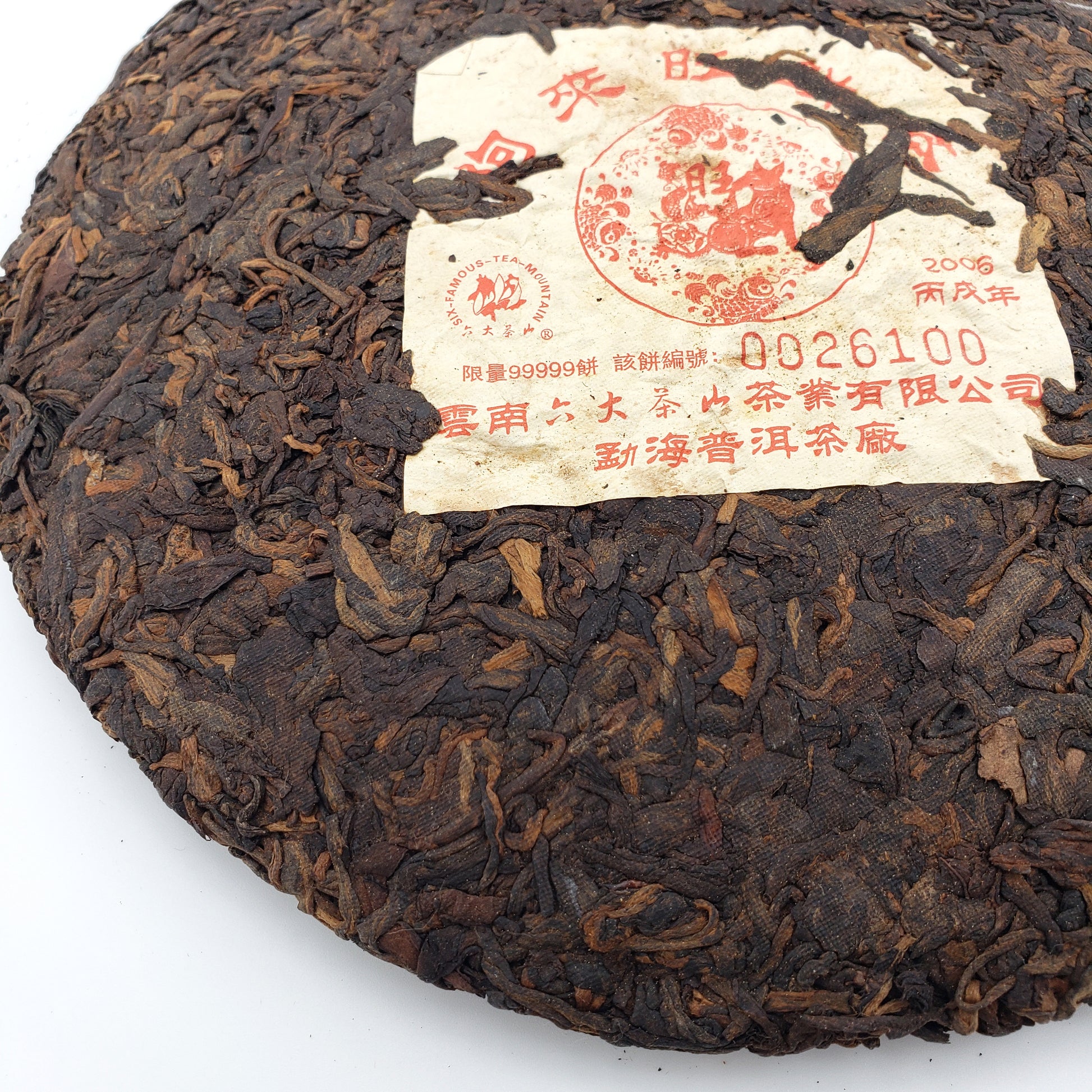 Round dark brown tea cake with a label on a white background
