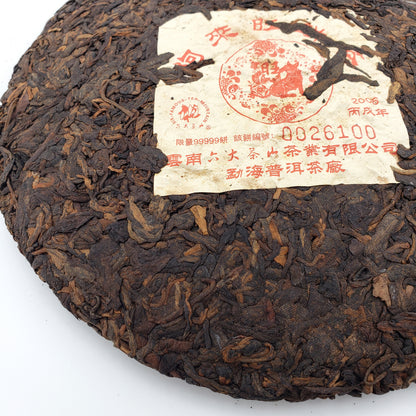 Round dark brown tea cake with a label on a white background
