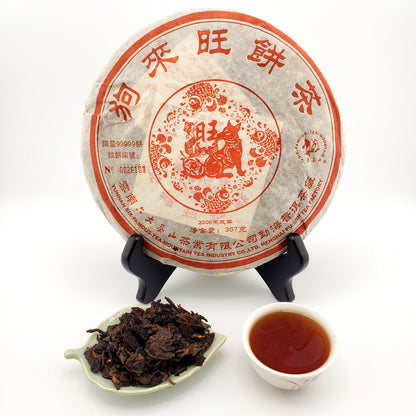 Pu-erh tea cake with a cup of tea and tea leaves on a white background