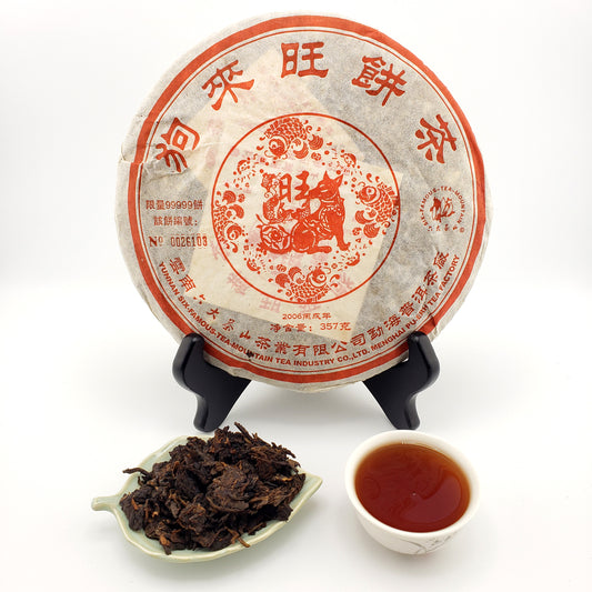 Pu-erh tea cake with a cup of tea and tea leaves on a white background