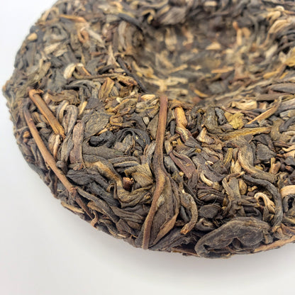 Close-up of a compressed tea cake with dried tea leaves on a white background