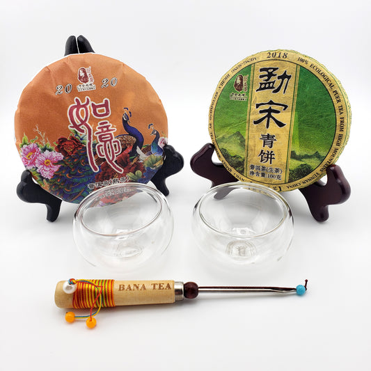Two tea cake packages with stands, two glass cups, and a tea tool on a white background.