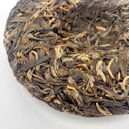 Close-up of a compressed tea cake with dried tea leaves on a white background