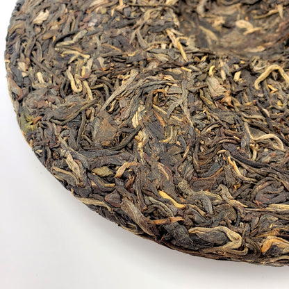 Close-up of a round cake of Pu-erh tea leaves on a white background