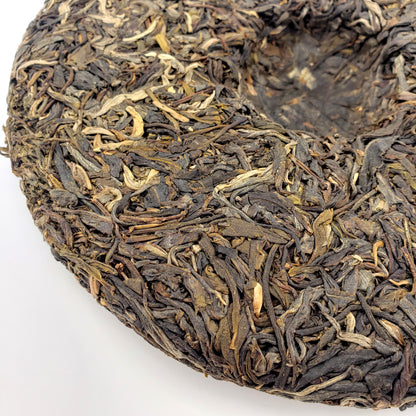 Close-up of a round cake of Pu-erh tea leaves on a white background