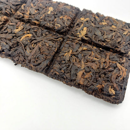 Close-up of a scored brick of Pu-erh tea on a white background