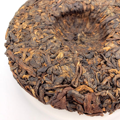 Close-up of a compressed tea cake with intricate texture on a white background
