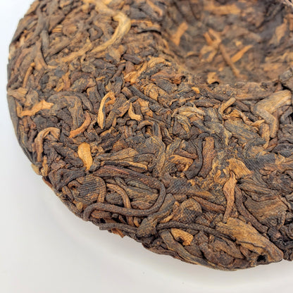 Close-up of a compressed tea cake with intricate texture on a white background