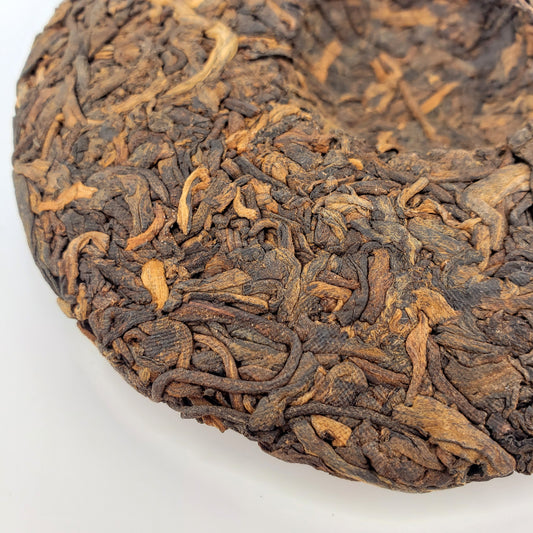 Close-up of a compressed tea cake with intricate texture on a white background