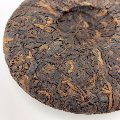 Close-up of a compressed tea cake with intricate texture on a white background