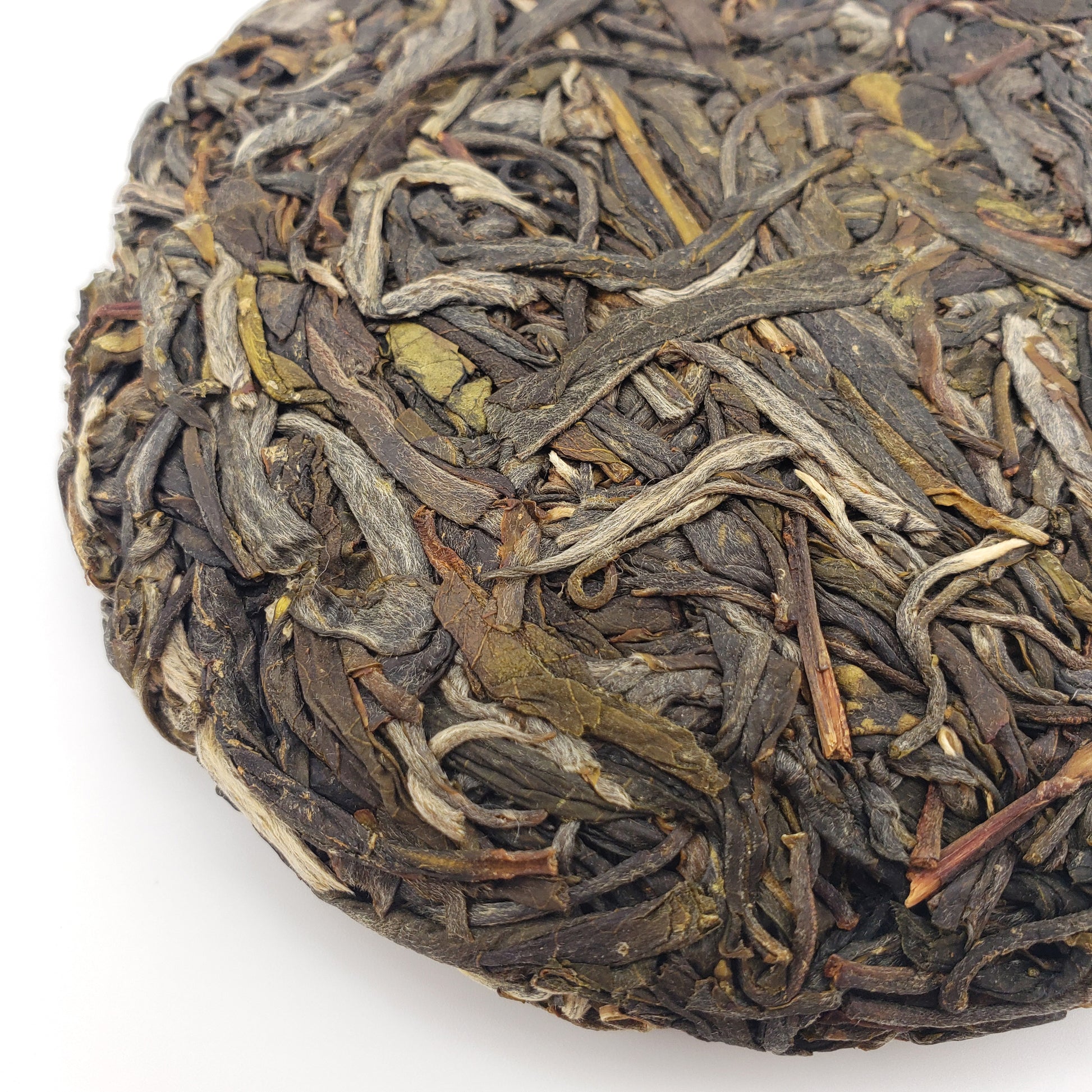 A close-up of a round compressed cake of Pu-erh tea leaves on a plain white background.