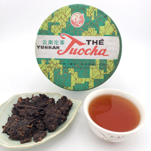 Yunnan Pu-erh tea packaging, tea leaves, and a cup of tea on a white background