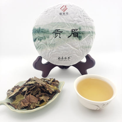 Tea cake, teacup with tea, and scoop of tea leaves on a white background