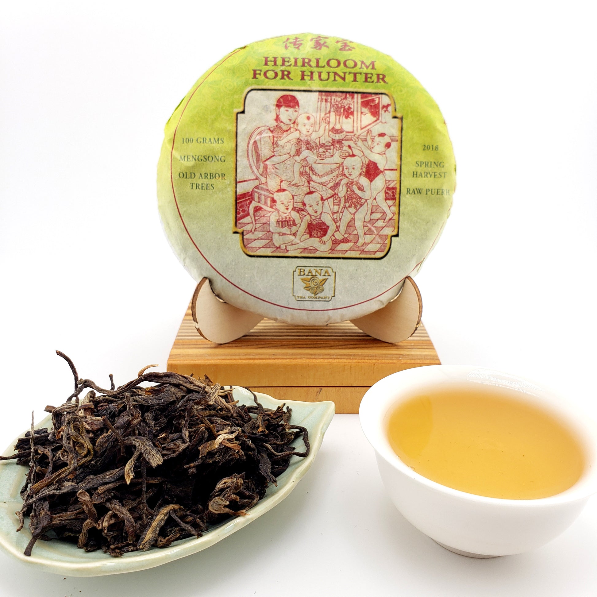 Tea cake with packaging, brewed tea in a cup, and loose tea leaves on a white background