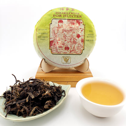Tea cake with packaging, brewed tea in a cup, and loose tea leaves on a white background