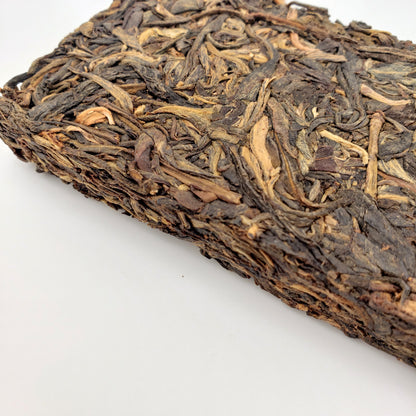 A block of aged tea with dark brown and beige colors on a white background